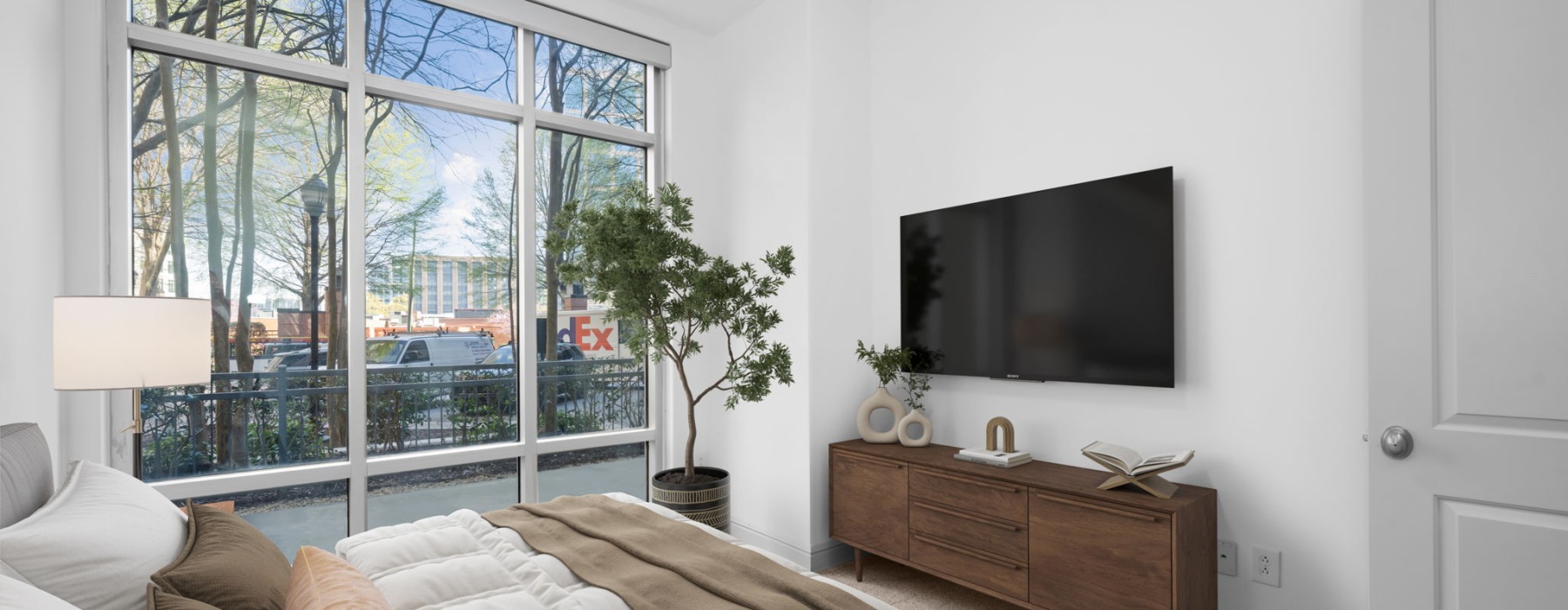 Light-filled bedroom with large windows, modern finishes, and outdoor terrace access at Ashton South End apartments in Charlotte