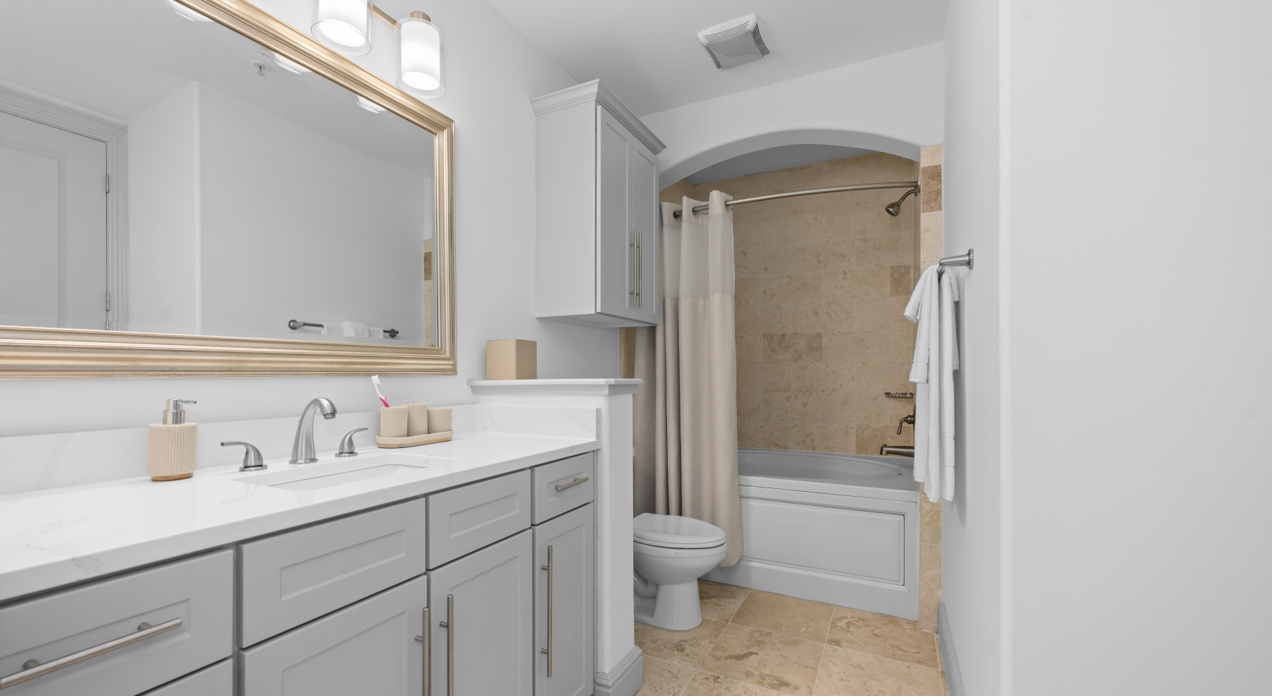 Contemporary apartment bathroom with dual sink vanity, large mirror, neutral tile flooring, and tub shower combination in Charlotte South End