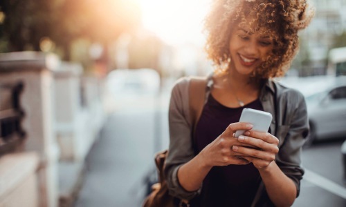 woman walking in the city while looking at her phone